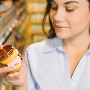 Mujer leyendo etiqueta nutricional con un frasco de colado para bebes
