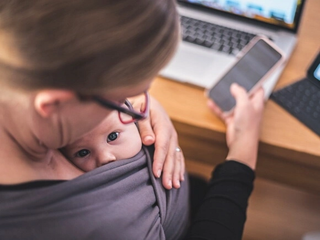 Madre trabajando con su hijo en brazos