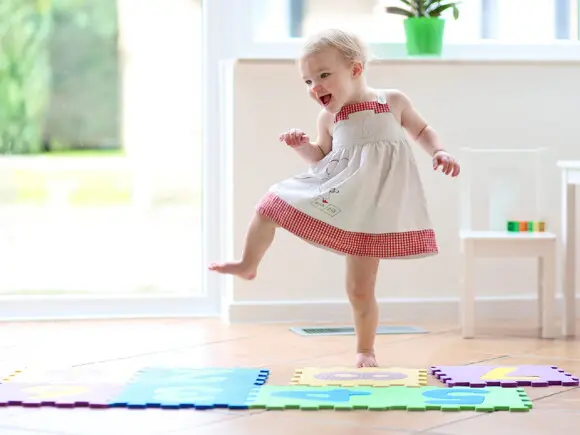 niña bailando sobre tapetes de goma para jugar