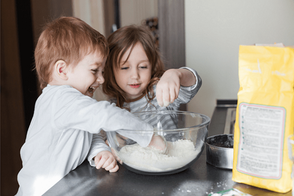 Snacks para el Día del Niño niño y niña cocinando juntos en un bol lleno de harina