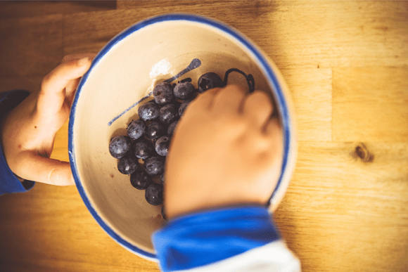Snacks para el Día del Niño niño comiendo uvas de un recipiente